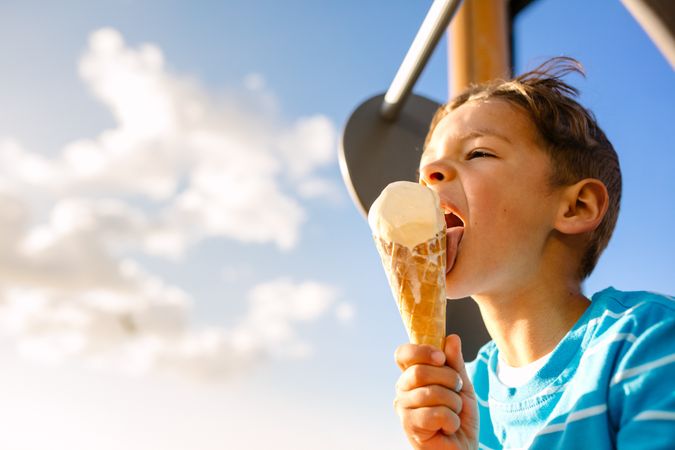 Close up of a boy licking an ice cream on a bright sunny day