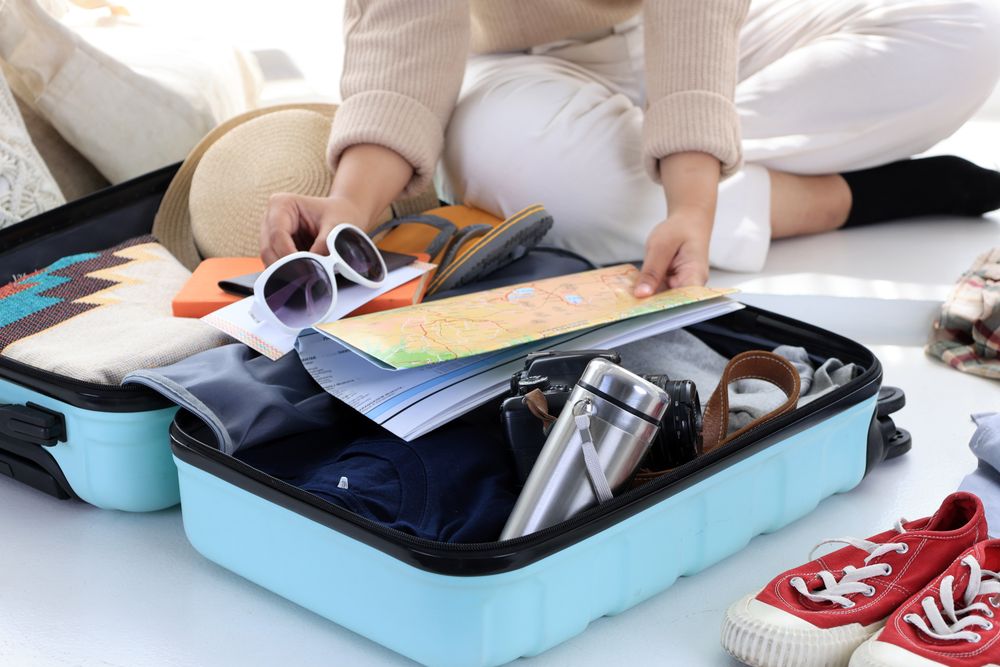 Happy Asian Young Woman Packing Suitcase at Home.
