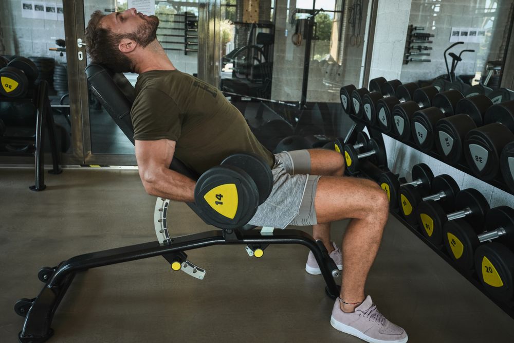 Strong man exercising with dumbbells in gym