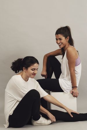 Happy young sportswomen resting after training in studio