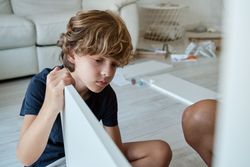 Focused boy helping mother to assemble furniture