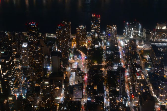 Top Down Aerial View of New York City Streets Lit with Neon Lights from Billboards. Busy Metropolis Traffic with Cars, Yellow Taxis, Commercial Vehicles and People Walking