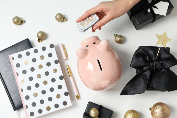 Piggy bank, balls, gift boxes and female hand on neutral background, top view