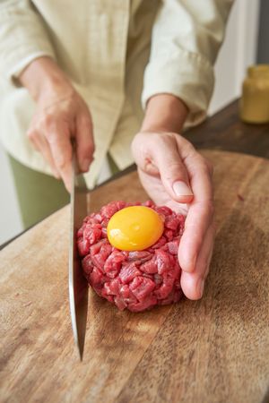 Faceless woman preparing delicious steak tartare for dinner at h