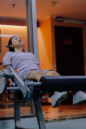 A woman is using a leg extension machine in a gym