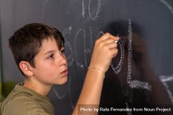 Teenage male writing on chalkboard 4myNW4