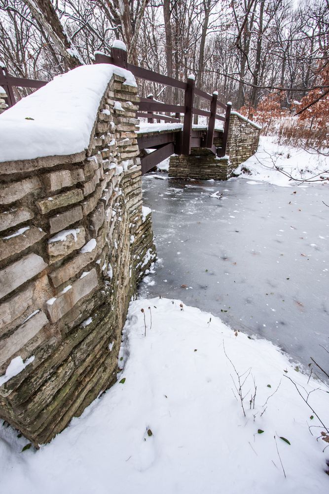 Rustic Bridge Over Frozen River In Winter.