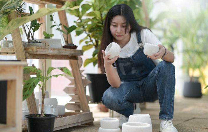 Asian female examining plant pots at work