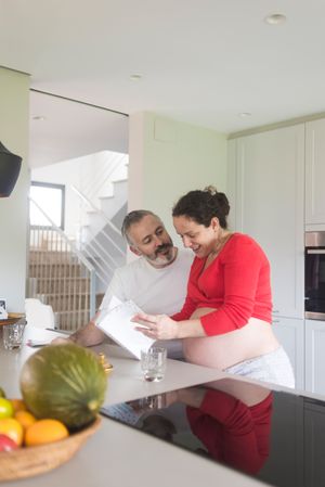 Pregnant woman and husband deciding what to cook from book