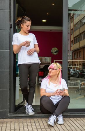 Two hair stylists sitting outside of salon during break