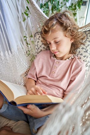 Child with book lying in hammock