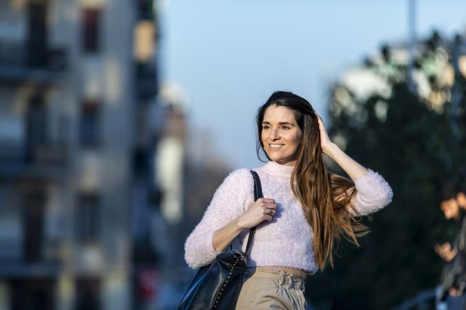 Long haired woman with handbag outside at dusk