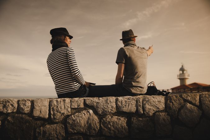Man and woman on stones near lighthouse