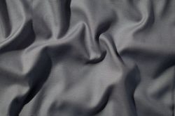 Crumpled wavy dark grey silky fabric background texture. siny and glossy.