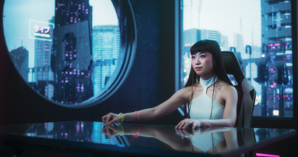 She is Using Glass Interactive Desk with Futuristic Cyberpunk City in the Background
