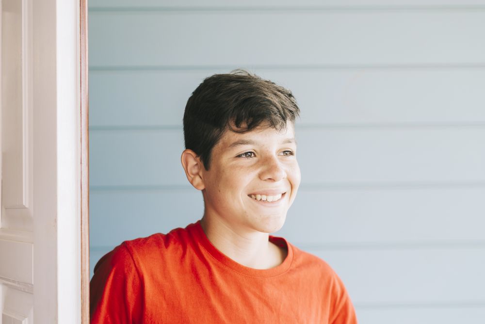 Happy male teen standing in doorway while looking away