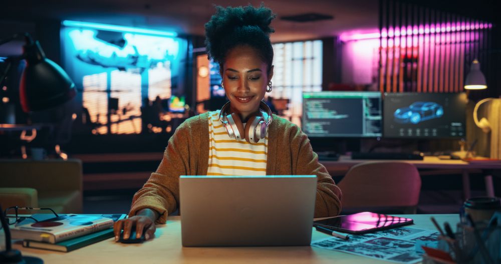 Portrait of a Black Smiling Female, Using Laptop Computer, Smiling in a Creative Office.