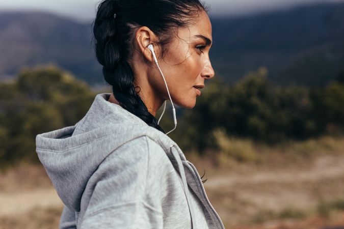 Profile shot of young woman on trail pathway with earphones
