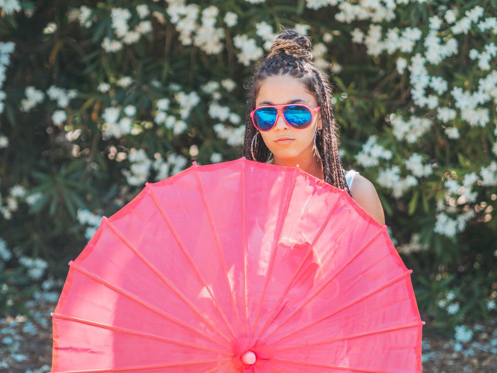 Fit young female with umbrella standing near blooming trees