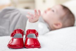 Baby red shoes and babe lying on the background