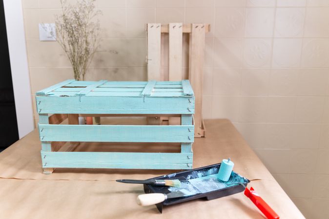 Freshly painted wooden box and paint tray on table