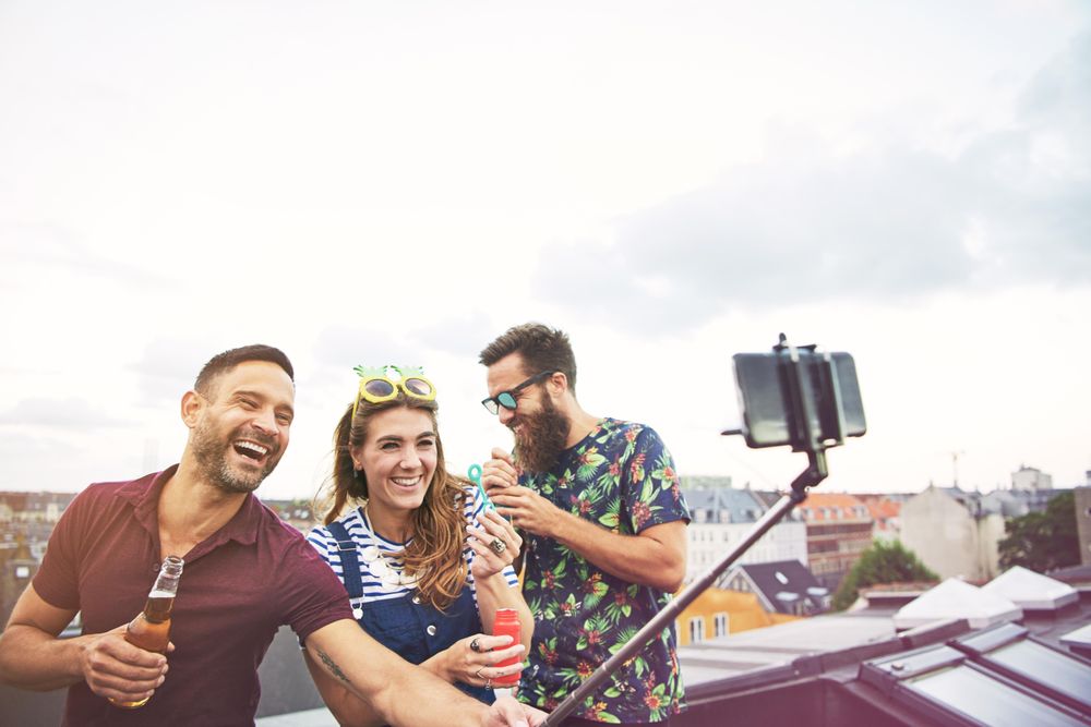 Friends laughing while blowing bubbles with selfie stick