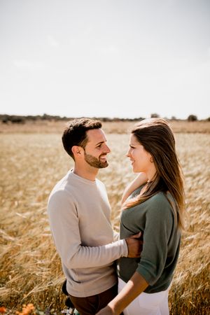 Sincere lovers posing by bicycle on rye field