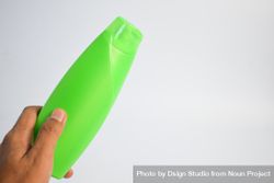 Person's hand holding green shampoo bottle 0WOOmP