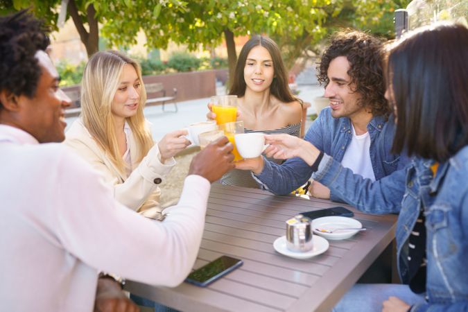 Friends celebrating with juice and coffee at an outdoor restaurant