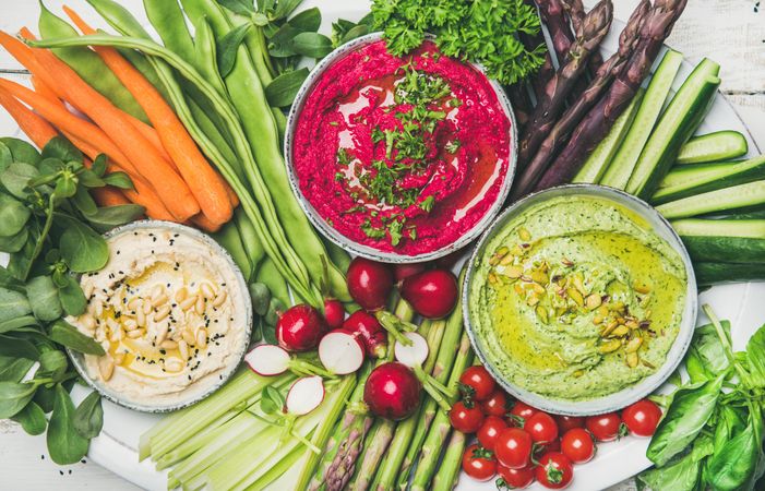 Top view of colorful vegetables and dips with hummus, avocados, asparagus, carrots