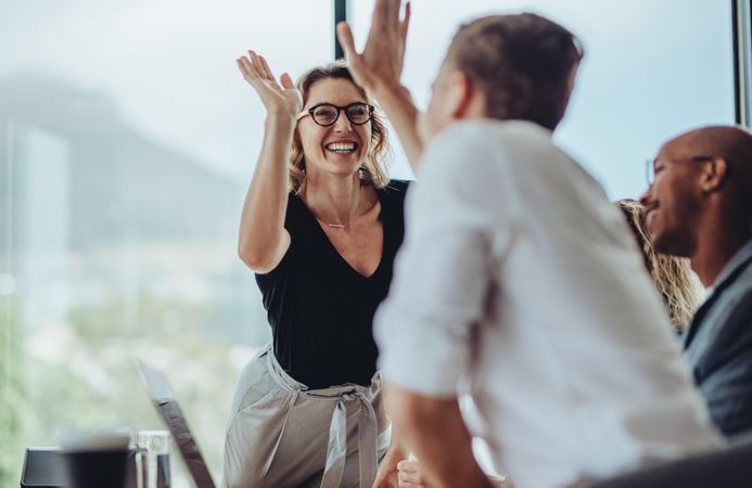 Businesswoman giving a high five to male colleague in meeting