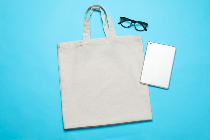 Eco bag, tablet and glasses on color background, space for text