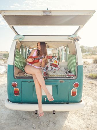 Woman playing ukulele sitting in trailer tank