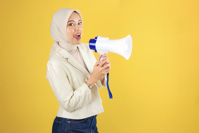 Happy Young Muslim Asian Woman is Announcing News or Discount Sale with Megaphone