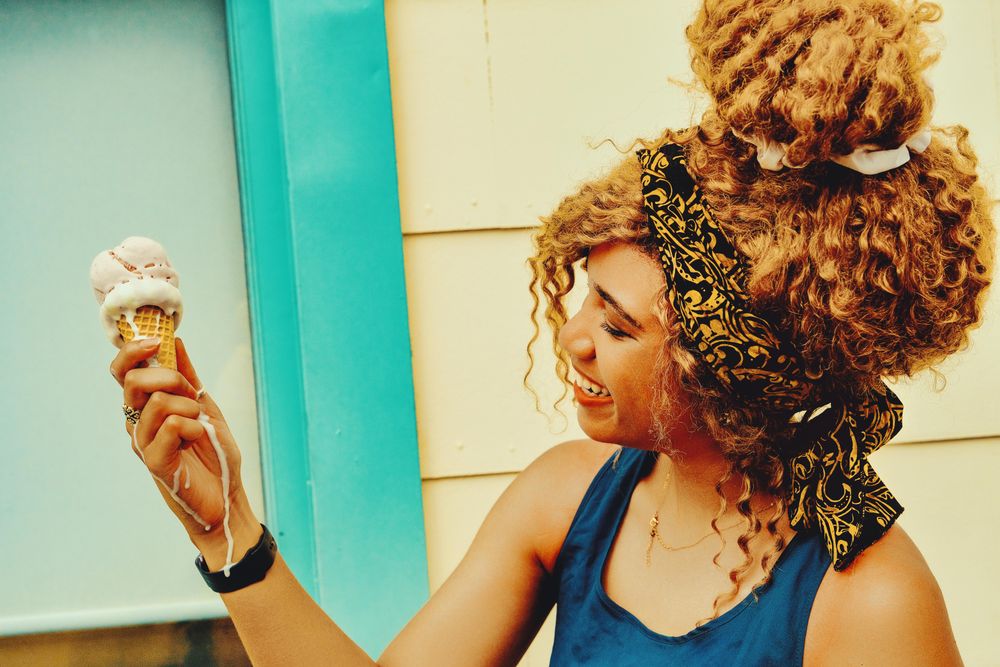 Black female looking at her ice cream cone in the sun, copy space