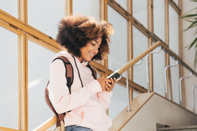 Teenage female student standing on stairs in school while texting