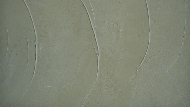 Smooth pale green concrete wall with plaster texture and curved surface pattern