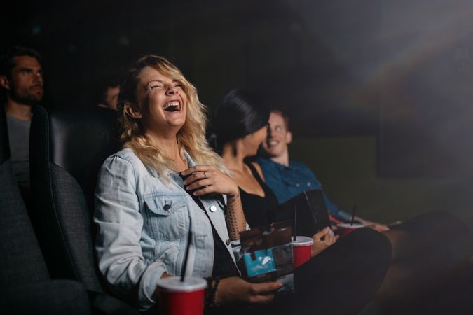 Young people watching movie in cinema and laughing