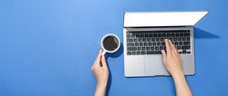 Looking down at person using laptop in a blue room with coffee with blank screen