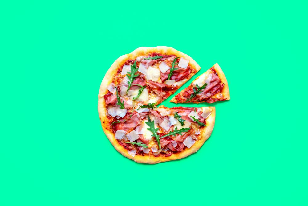 Homemade pizza with prosciutto, above view on a green table