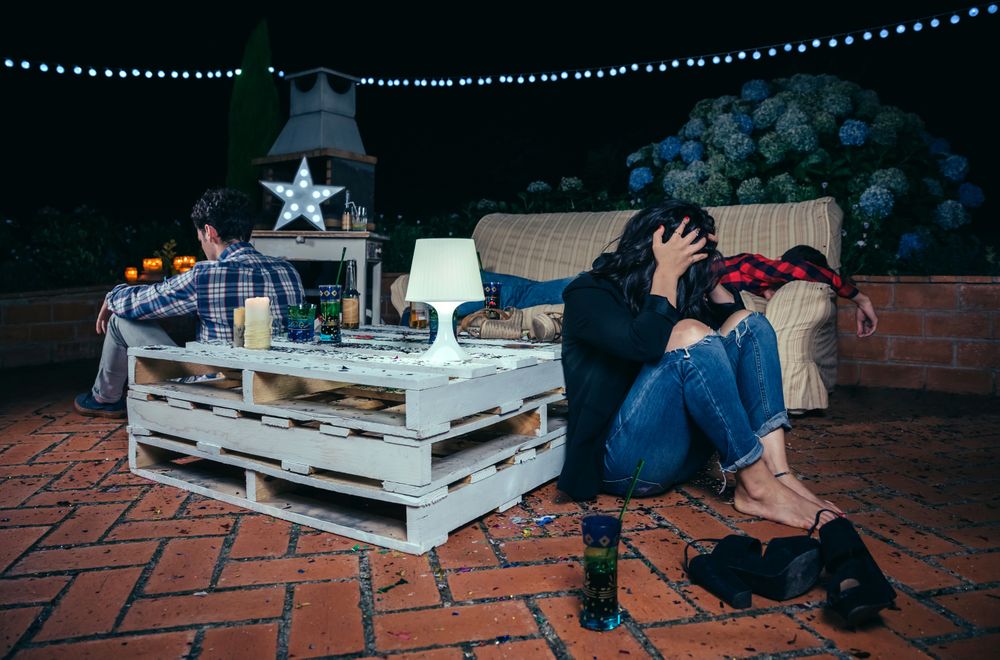 Inebriated young people hanging around sofa after the party