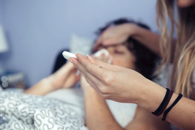 Woman looking at temperature of sick boyfriend