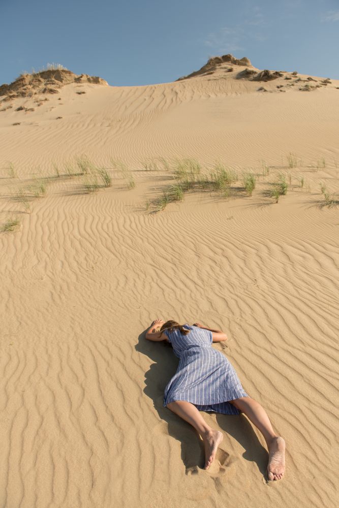 Young woman lying down on sand dune