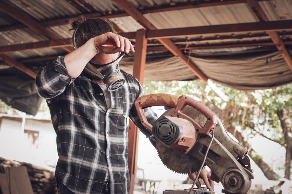 Carpenter tired from work using circular electric saw in workshop