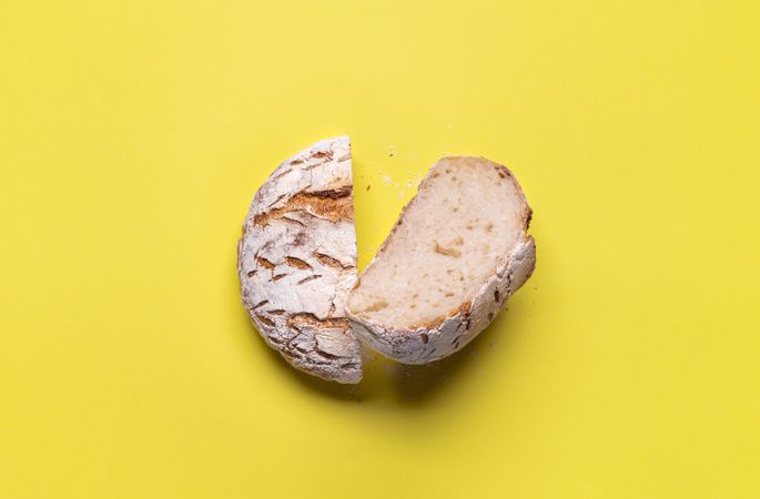 Loaf of bread split in half on yellow background
