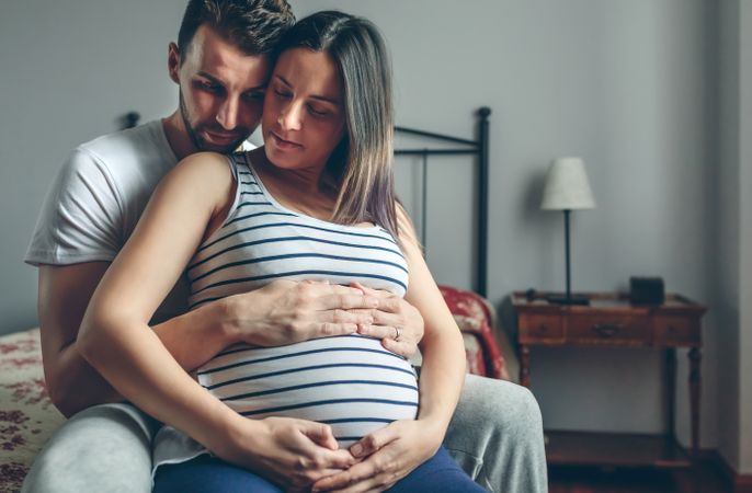 Pregnant woman embraced by her husband
