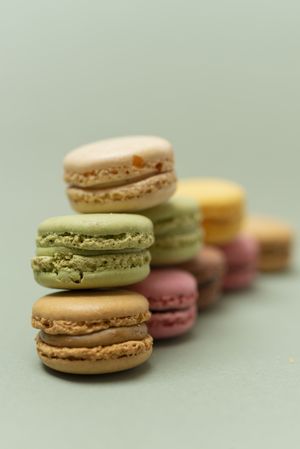 Pile of sweet pastel macaroons over a green background, vertical