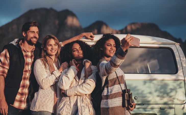 Group of mixed race friends taking a selfie near the van