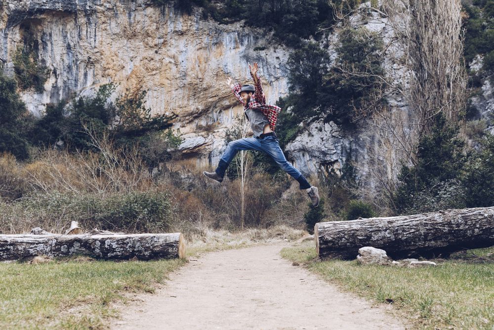 Excited man jumping on trunk in nature