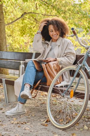 Smiling Black Latina woman sitting on bench in park